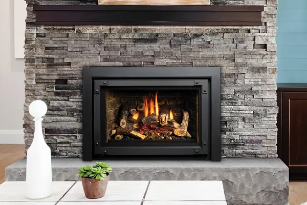 Gas fireplace insert in a stacked-stone surround between pale living-room chairs.